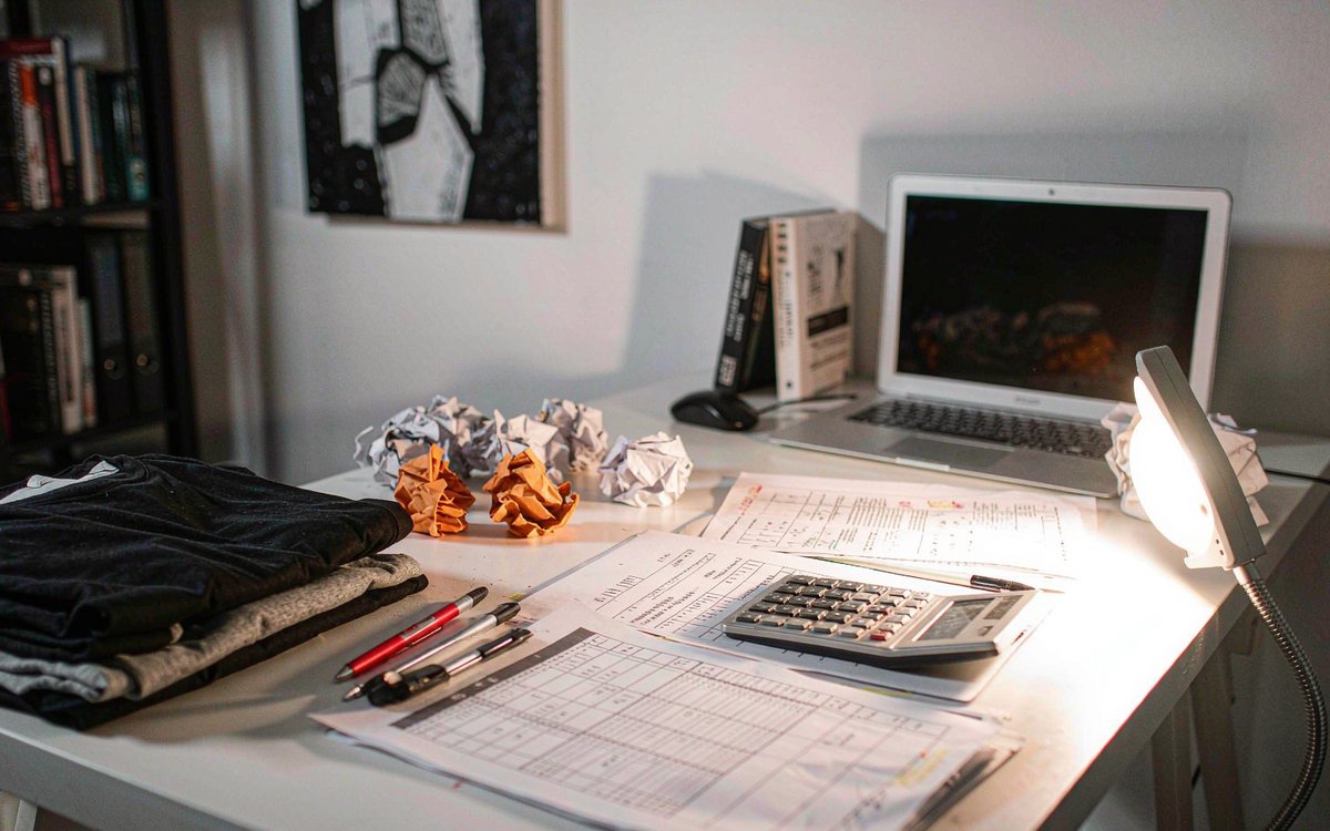 A simple size and sell-through tracking sheet next to folded garments and a calculator