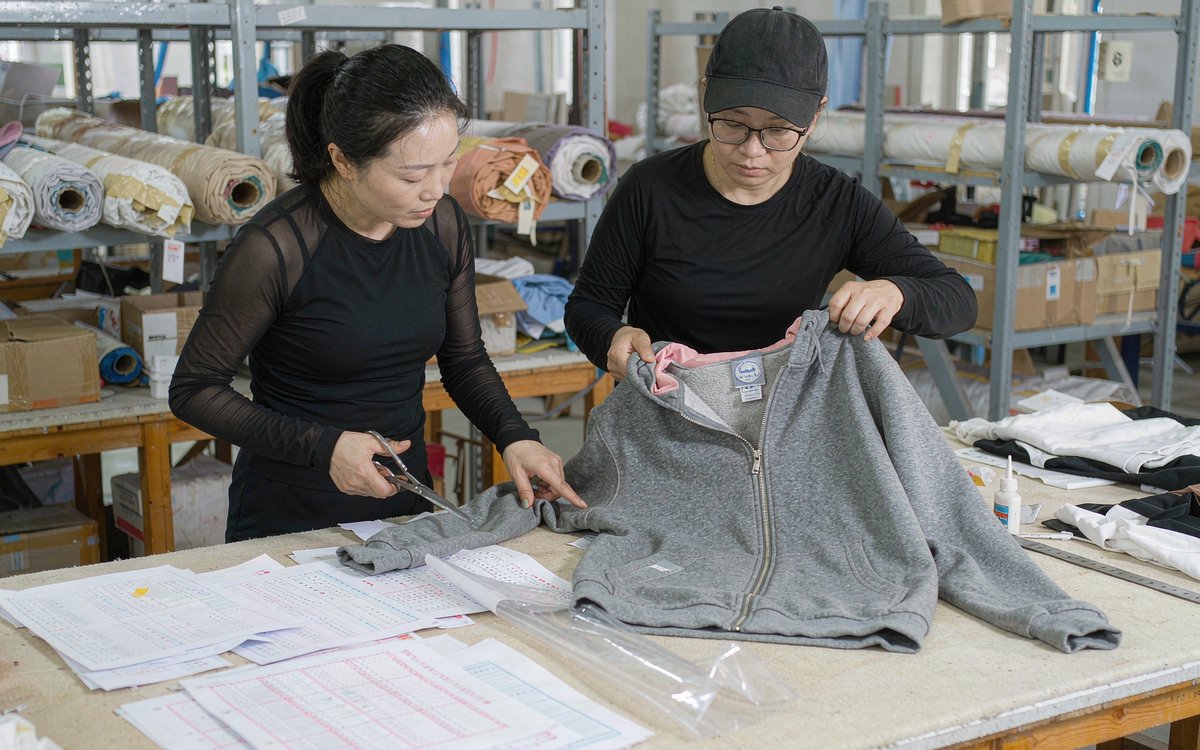 A brand founder and a factory representative reviewing a hoodie sample together at a worktable
