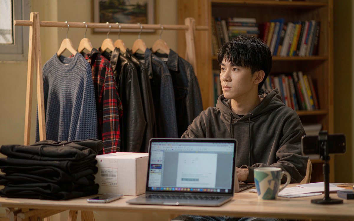 Founder of a small clothing brand packing orders in a home studio with cardboard boxes and folded garments